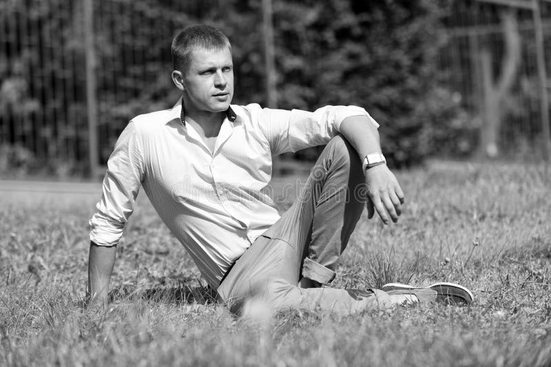 Man relax on green grass. Businessman in shirt and pants on sunny outdoor. Handsome macho enjoy summer day. Fashion royalty free stock photos Man relax on green grass. Businessman in shirt and pants on sunny outdoor. Handsome macho enjoy summer day. Fashion royalty free stock photos