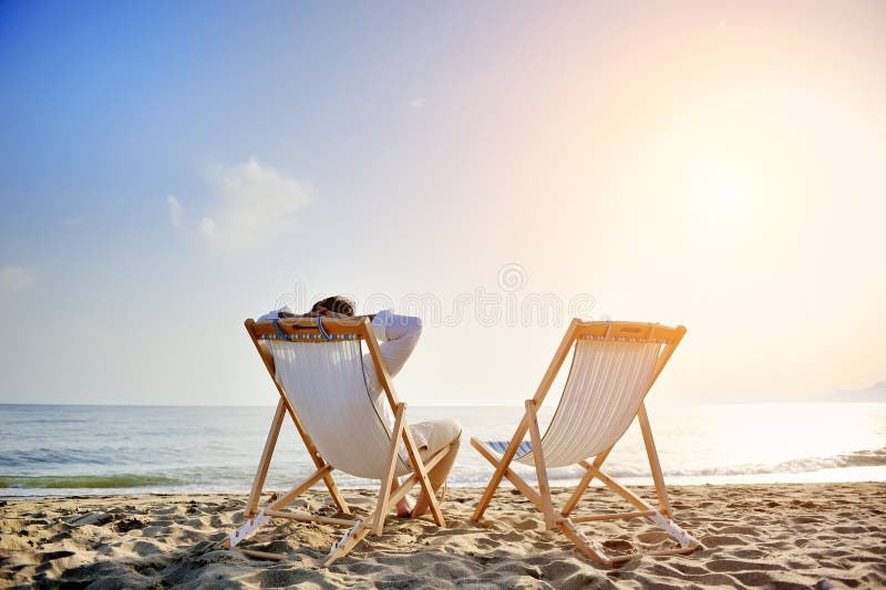 Hombre sobre el Playa relajante sobre el cubierta sillas espera su novia.