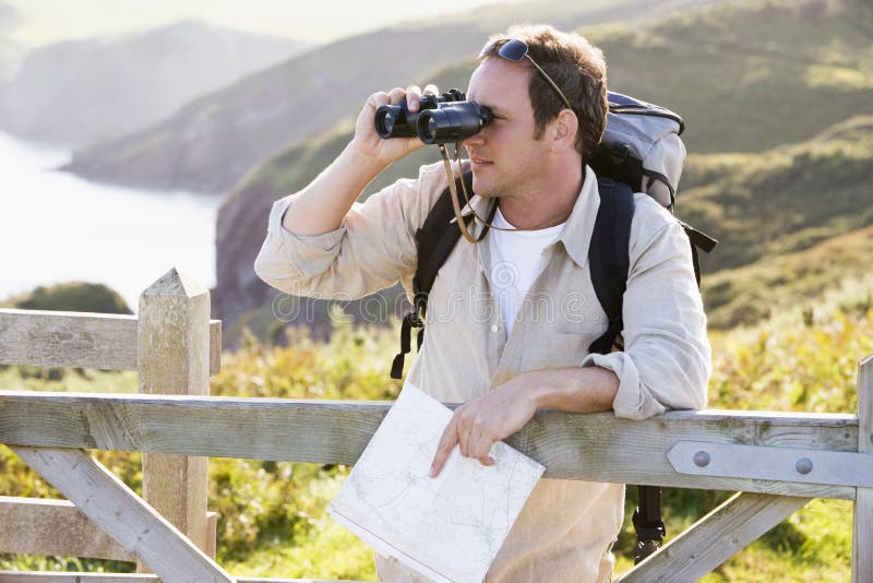 Man relaxing on cliff side path holding map