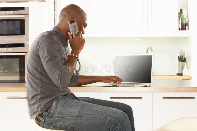 Man Relaxing Sitting In Kitchen Talking On Phone