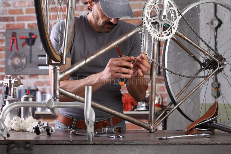 Man repair the vintage bicycle in garage workshop on the workbench with tools, diy concept