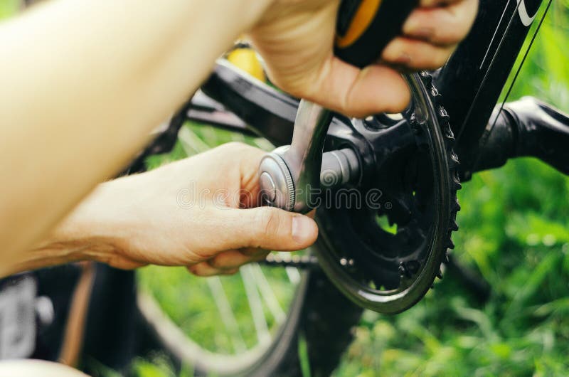 A Man Repairs a Chain on a Mountain Bike with a Socket Wrench on the