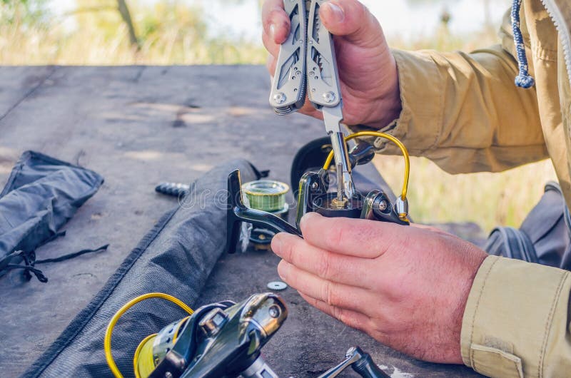 A man repairs a fishing reel with improvised means
