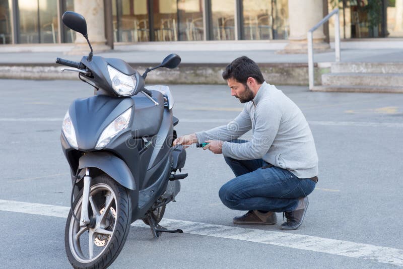 Man repairs a scooter stock image. Image of unscrew, wheel 66509085