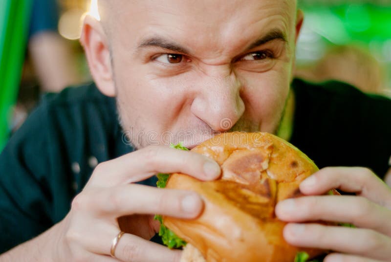 Целый голодный. Человек кусает бургер. Грустный человек ест гамбургер. Голодный бургер. Он голодный.
