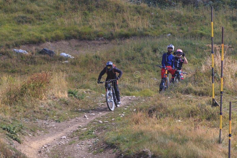 Man riding mountain bicycle downhill and two friends watching him royalty free stock images Man riding mountain bicycle downhill and two friends watching him royalty free stock images