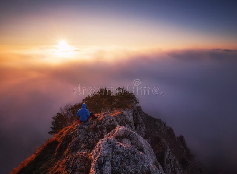 Man on rock above valley within daybreak and watch to hot Sun. Beautiful moment the miracle of nature