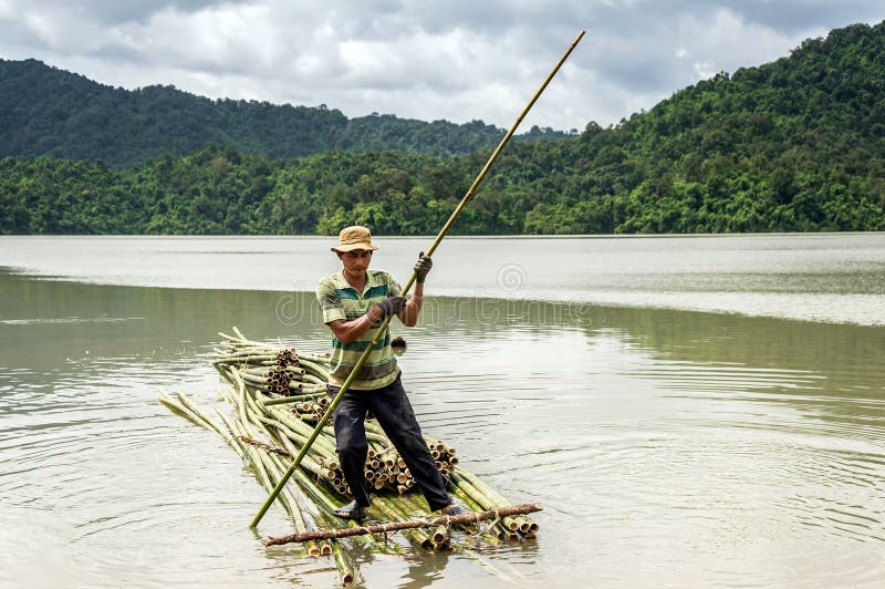 A man rowing the bamboo raft on the lake royalty free stock photo A man rowing the bamboo raft on the lake royalty free stock photo