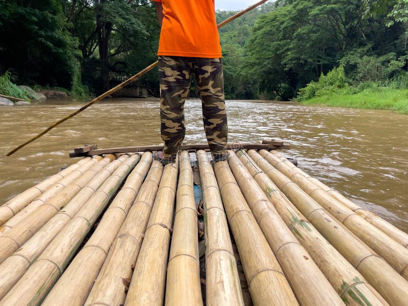 Man Rowing Bamboo Raft. Man Uses a Bamboo To Push a Raft on a River and See the Nature of the