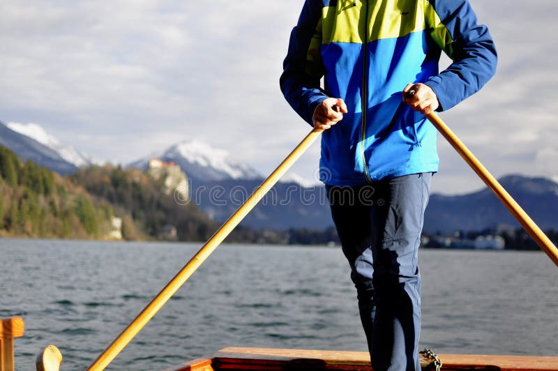 Man rowing on the typical wooden boat Pletna in the lake Bled, Slovenia, at sunset. Tourism, sport, exploring concept stock photo Man rowing on the typical wooden boat Pletna in the lake Bled, Slovenia, at sunset. Tourism, sport, exploring concept stock photo