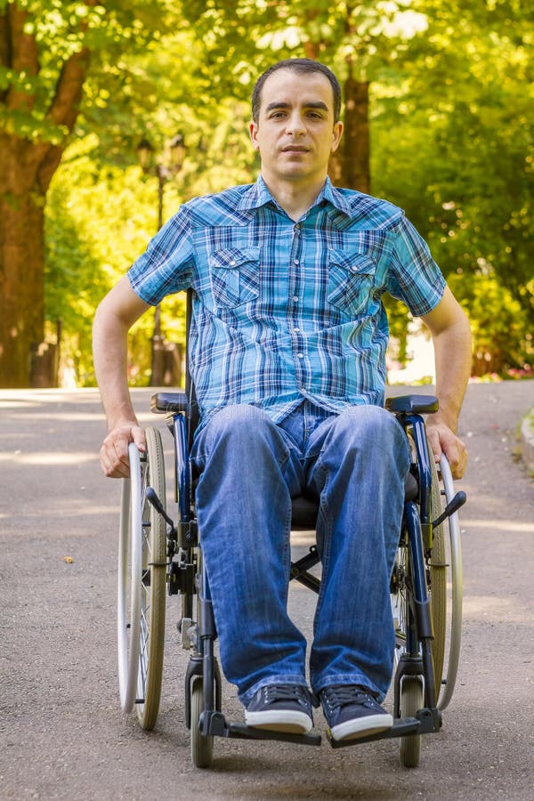 Young man in wheelchair in city park. Young man in wheelchair in city park.