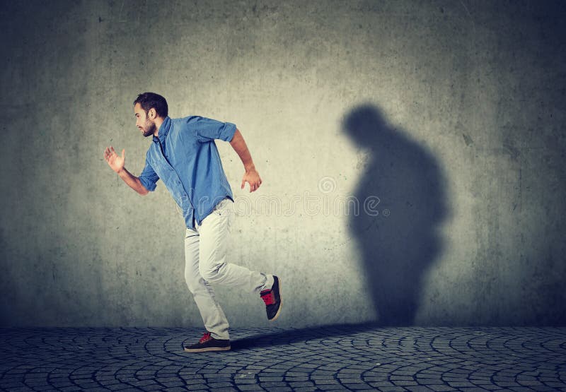 Man running away from his sad gloomy fat shadow on the wall