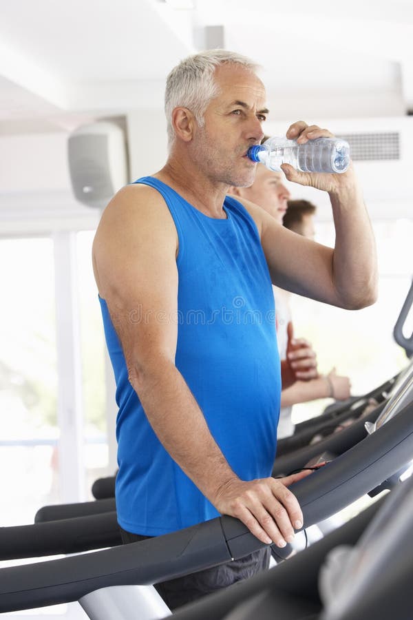 Man on Running Machine in Gym Drinking Water Stock Photo Image of group, dehydration 55895976
