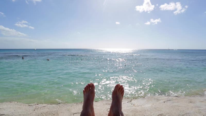 Man s feet relaxing by the ocean on a sunny day with clear blue sky