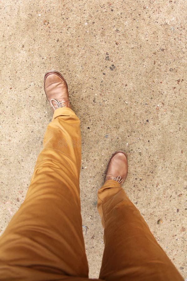 Man s feet in shoes walking on a park lane.