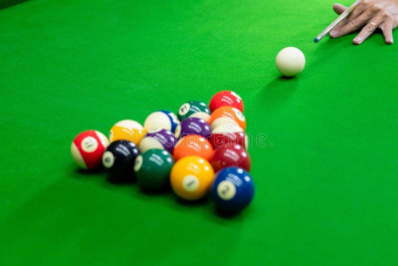 Man`s hand and Cue arm playing snooker game or preparing aiming to shoot pool balls on a green billiard table