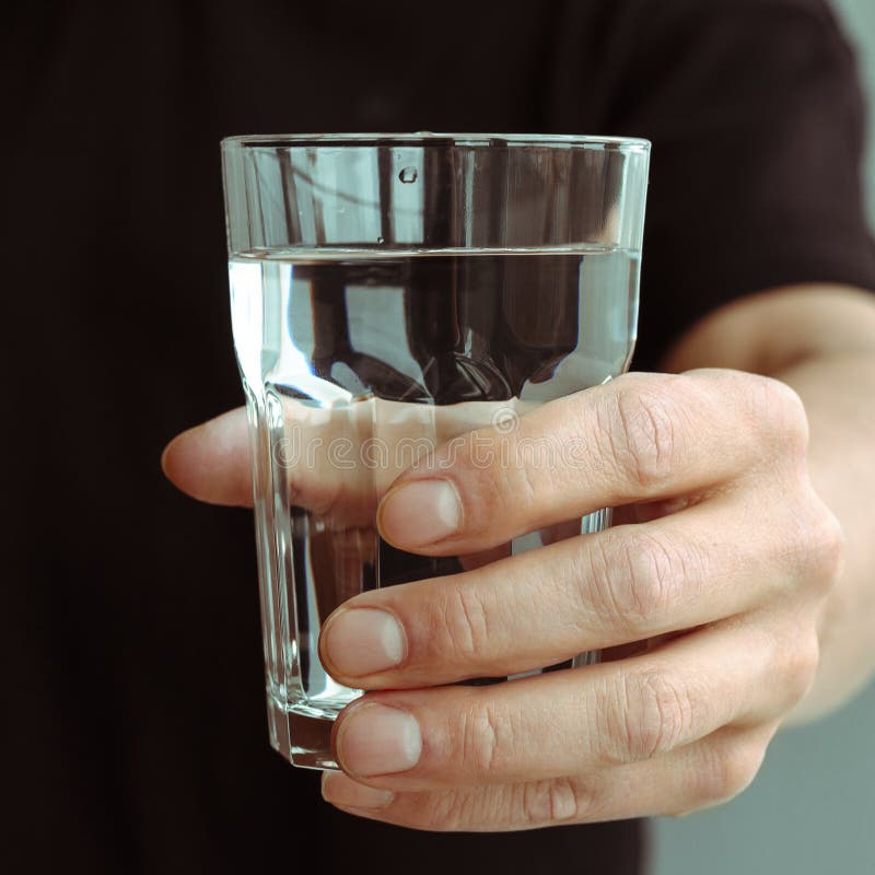 A man& x27;s hand with a glass of pure spring water