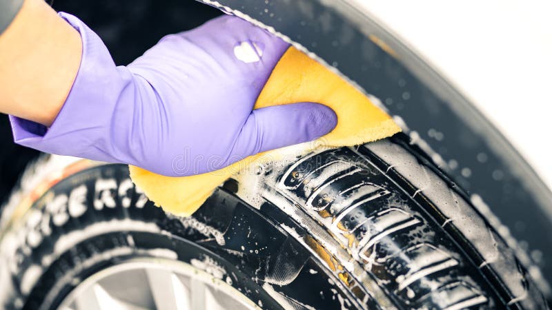 Man`s hand in gloves. a man washes a car wheel.