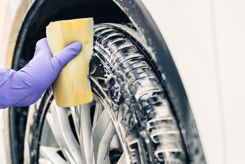 Man's hand in gloves. a man washes a car wheel.