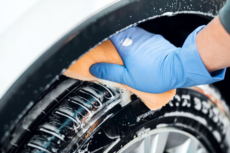 Man`s hand in gloves. a man washes a car wheel.