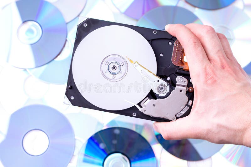 Man s hand with hard disk drive over CD s background.