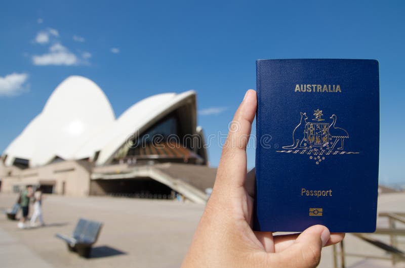 A man`s hand holding Australia passport with blurred background of Sydney Opera House for Concepts of traveling.