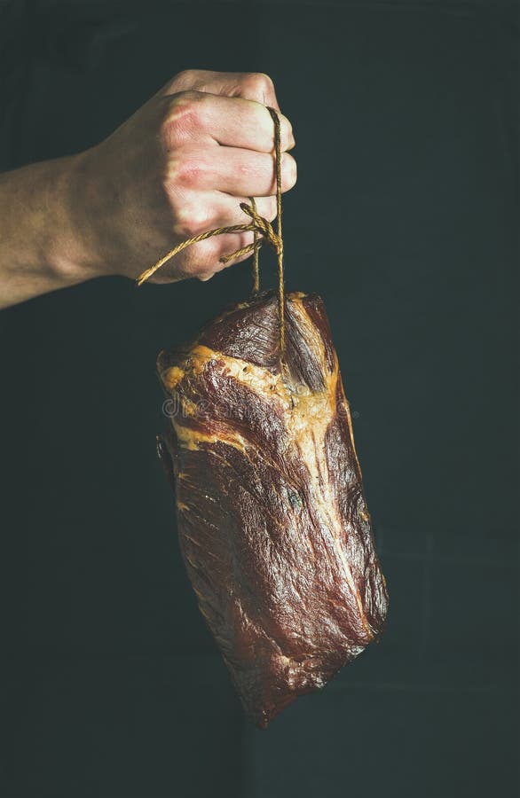 Man` s hand holding cut of cured pork meat