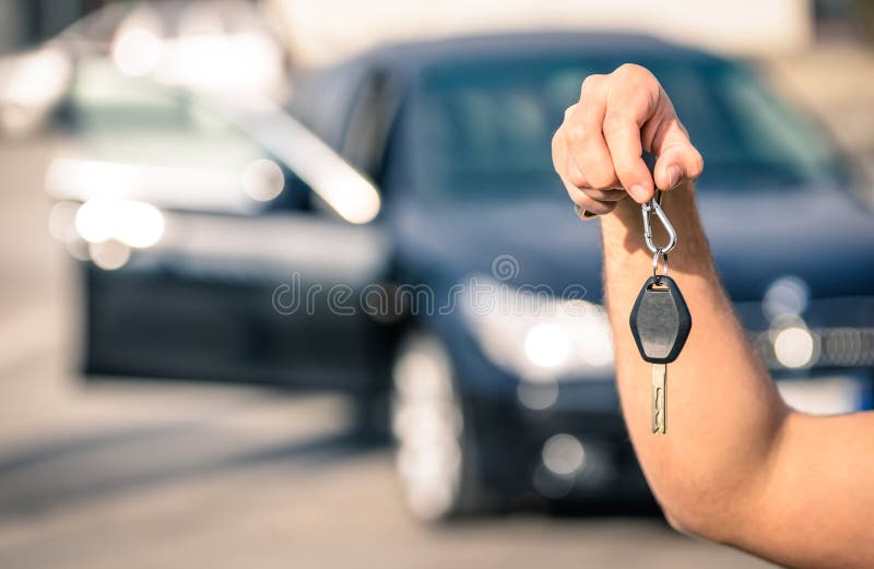 Man&x27;s hand holding modern car keys ready for rental