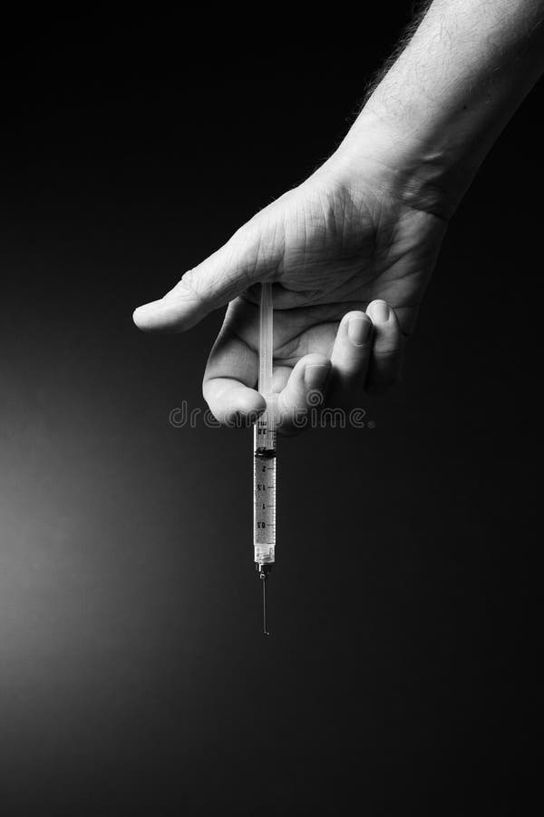 Man`s hand holding syringe with dramatic lighting stock images