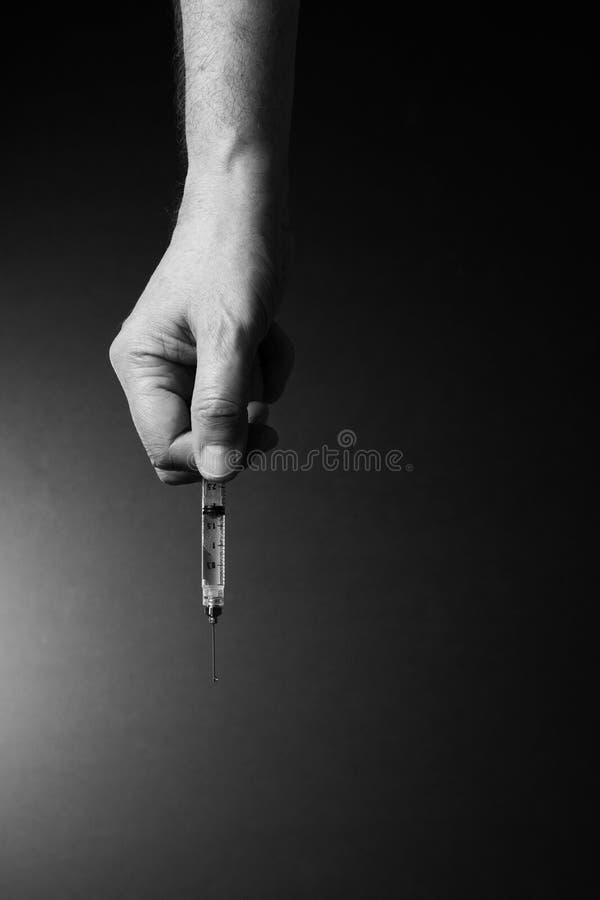 Man`s hand holding syringe with dramatic lighting stock photo