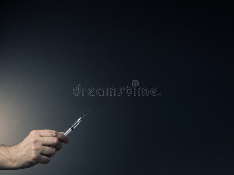 Man`s hand holding syringe with dramatic lighting royalty free stock image