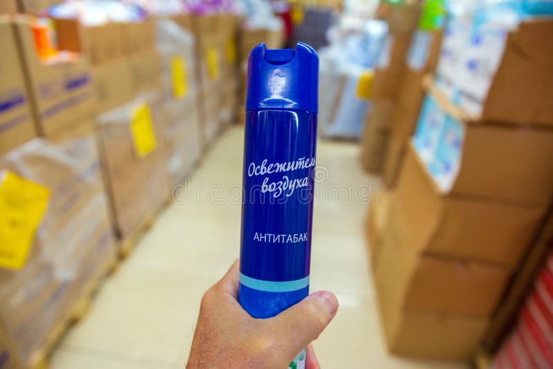 A man`s hand holds an air freshener while choosing in a store. Russian text: air freshener, anti-tobacco