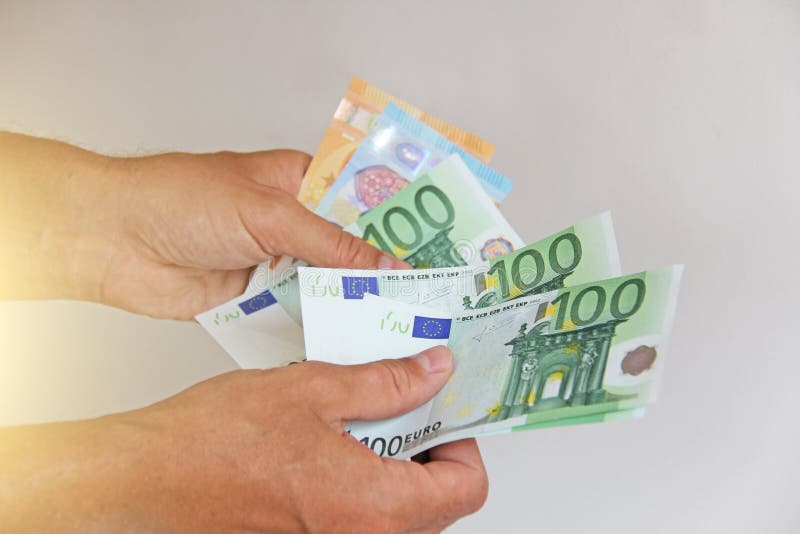 The man`s hand holds the 100 euro, considers them and pays. Paper money euros in the hands