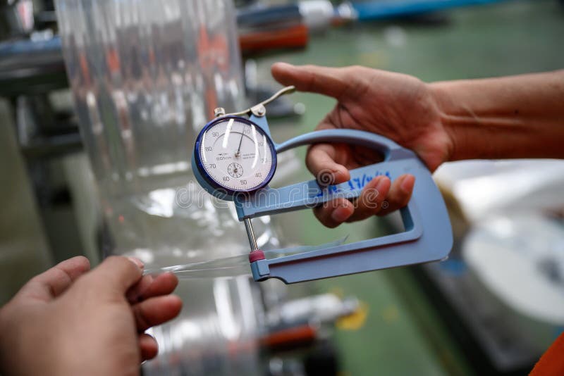 Man`s hand is measuring the thickness of the plastic bag type film Polypropylene To check and control the quality