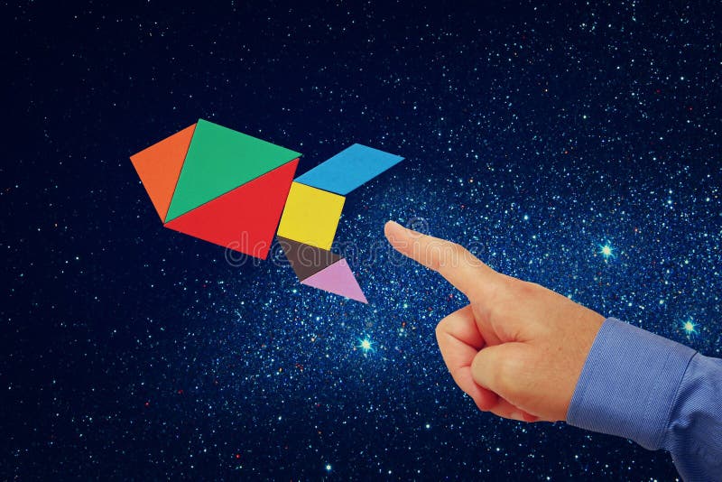 Man's hand pointing at rocket made from tangram puzzle stock image
