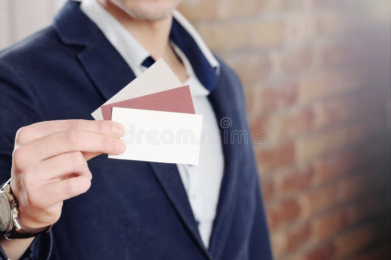Man s hand showing business card - closeup shot on brick wall background
