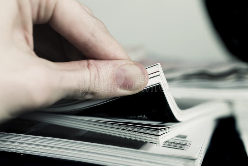 Man s hand turned over a stack of magazines