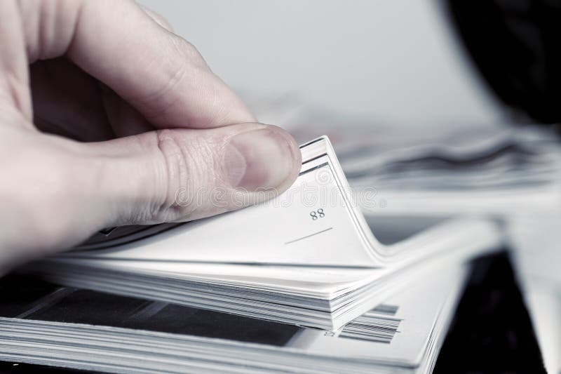 Man s hand turned over a stack of magazines