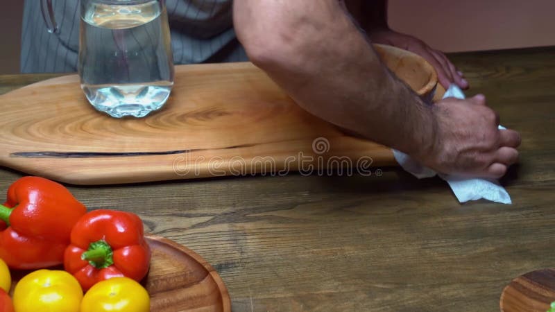 the man's hand wipes the table and cutting board with a rag. kitchen