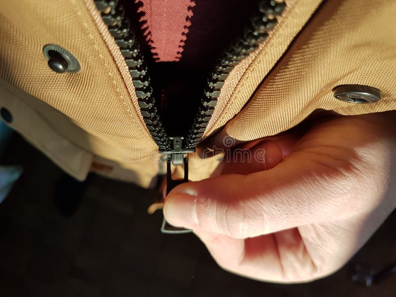 The Man`s Hand Zips Zip Up On The Jacket Zipper Close Up In Hard Light