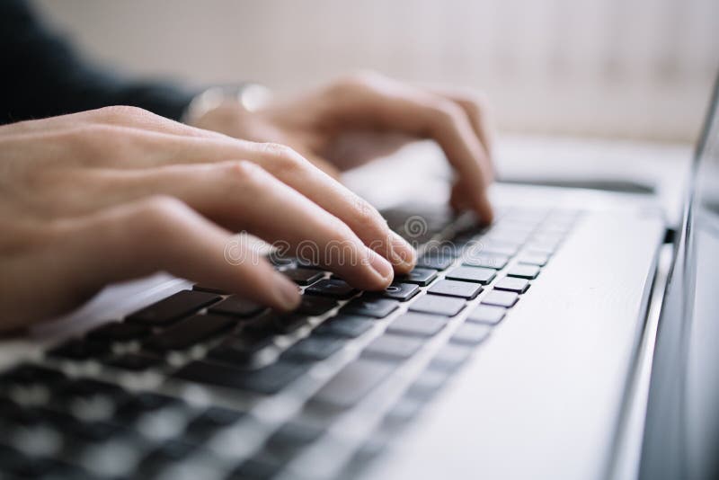 Man`s hands typing on a black keyboard