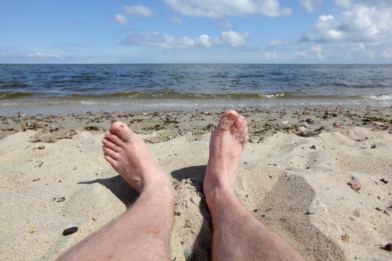 Man's legs on the beach - first person perspective stock photo
