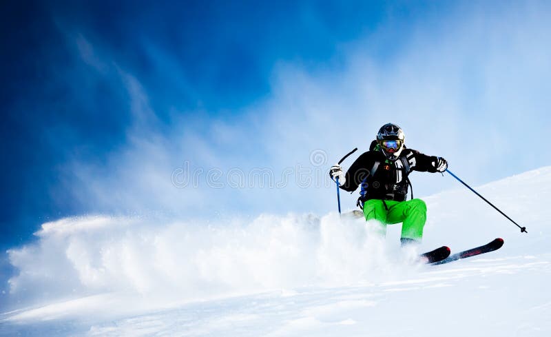 Joven masculino esquiador en el cielo azul encendido en polvo la nieve negro chaqueta verde peladura horizontalmente orientación.