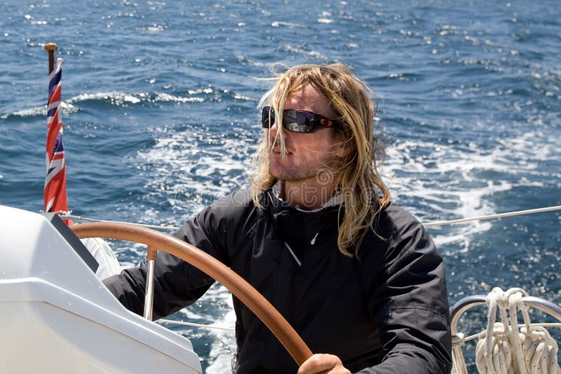 Man with blonde long hair sailing yacht. Man with blonde long hair sailing yacht