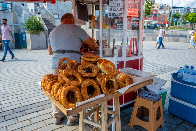 Man sale traditional Turkish bagel simit from cart on the summer Istanbul street