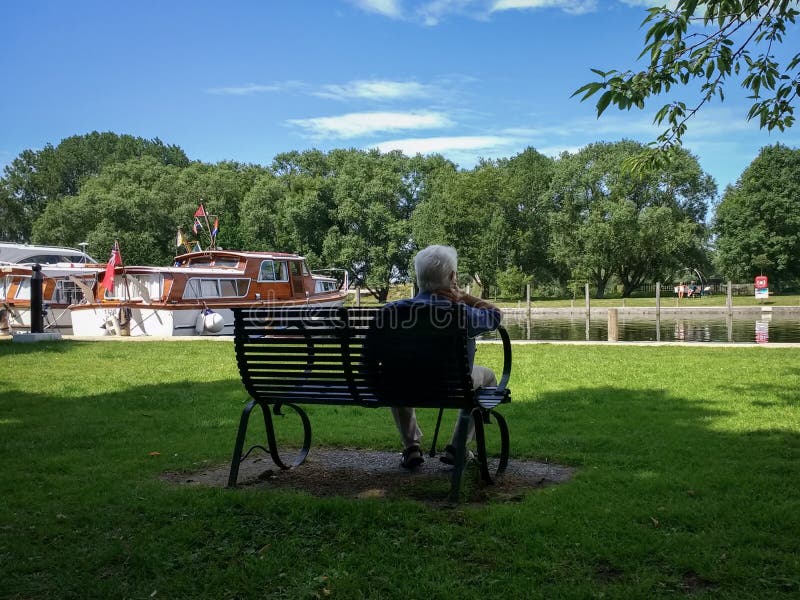 Man sat on a seat admiring the boats at Beccles Quay on the River Waveney royalty free stock photos Man sat on a seat admiring the boats at Beccles Quay on the River Waveney royalty free stock photos
