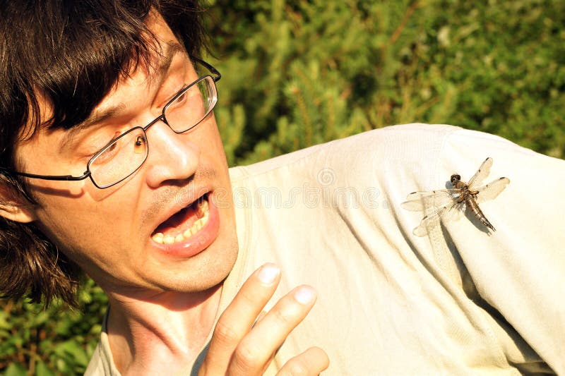 Man scared by dragonfly that sitting at his shoulder