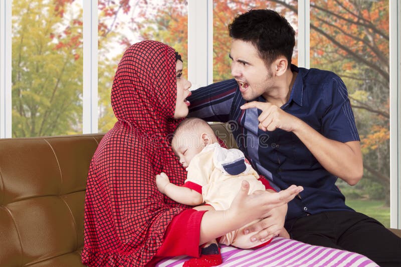Man scolding his wife while holding baby