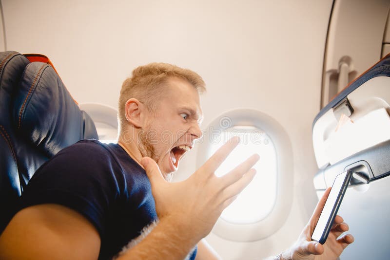 Man screams and resents cell phone on board airplane. Concept phobia and lack of internet addiction