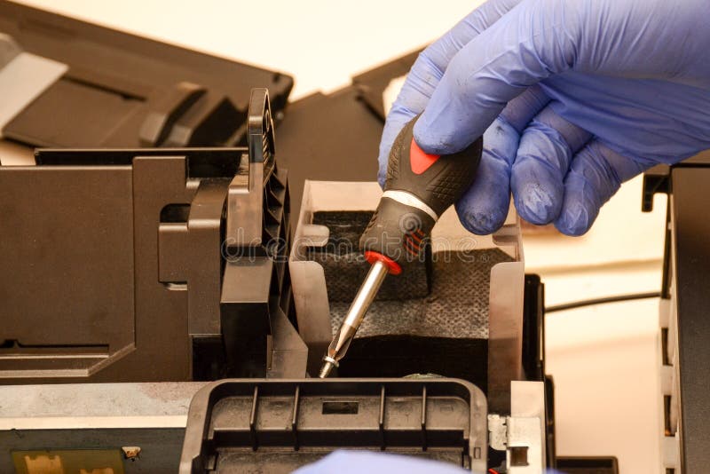 A Man with a Screwdriver Assembles a Printer. Repair of Office